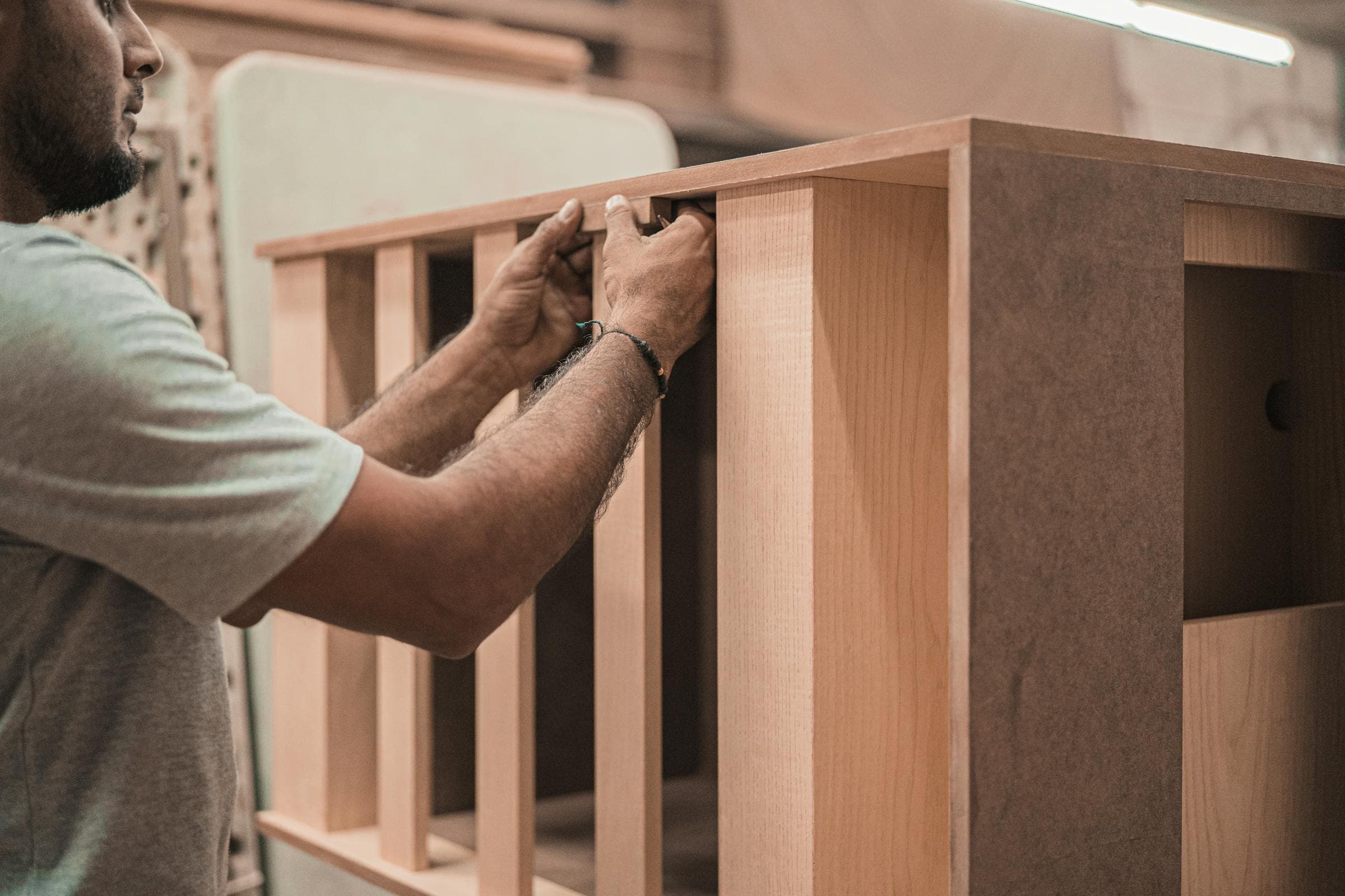 Craftsman aligning components by hand at a workshop bench